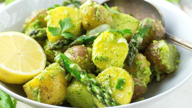 Close-up of pesto potato salad with asparagus, green onion, and lemon