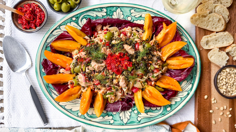 Italian-style tuna salad on serving platter with bread, pine nuts, olives, and chili paste
