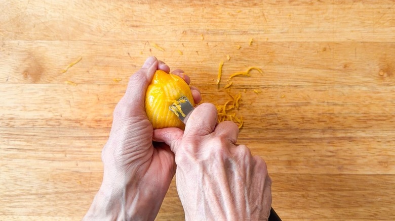 Zesting a lemon over a cutting board using a zester tool