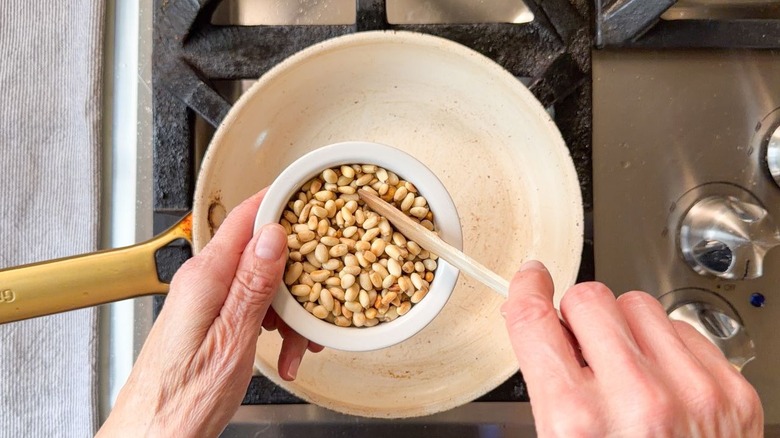 Transferring toasted pine nuts from skillet to small bowl to cool