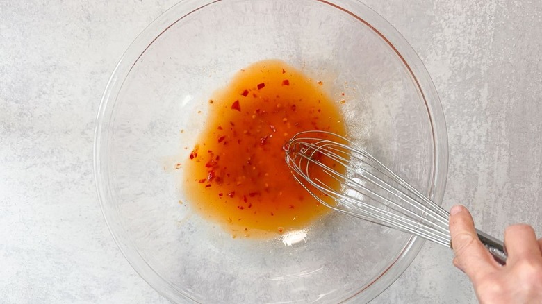 Whisking vinaigrette for Italian-style tuna salad in glass bowl
