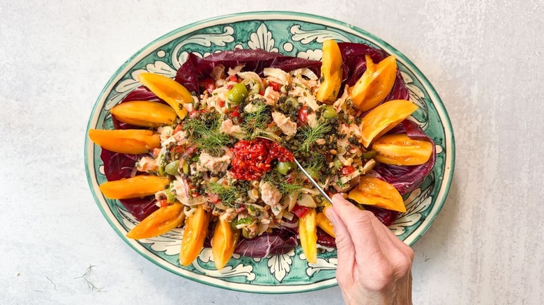 Garnishing Italian-style tuna salad on green and white platter