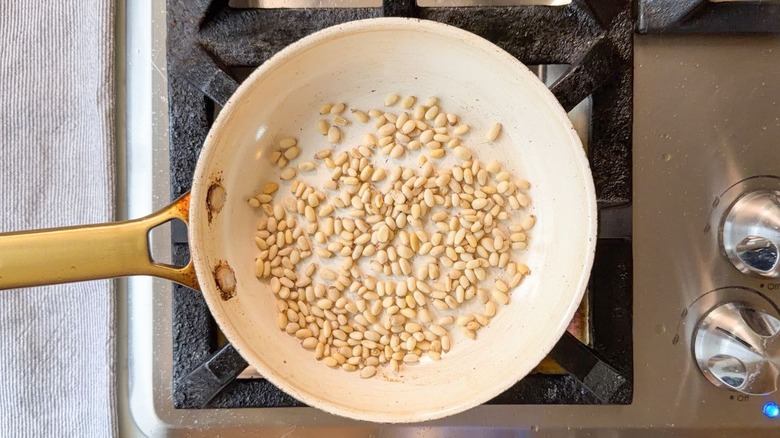 Pine nuts in white skillet on stovetop