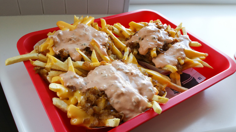 A red tray containing three orders of In-N-Out's Animal Style fries