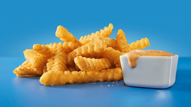 a pile of groovy fries with sauce on a blue background