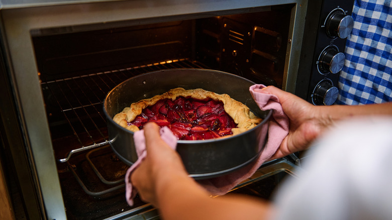 A person removing a freshly baked dessert from an oven.