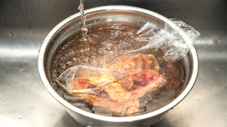 meat defrosting in bowl of water
