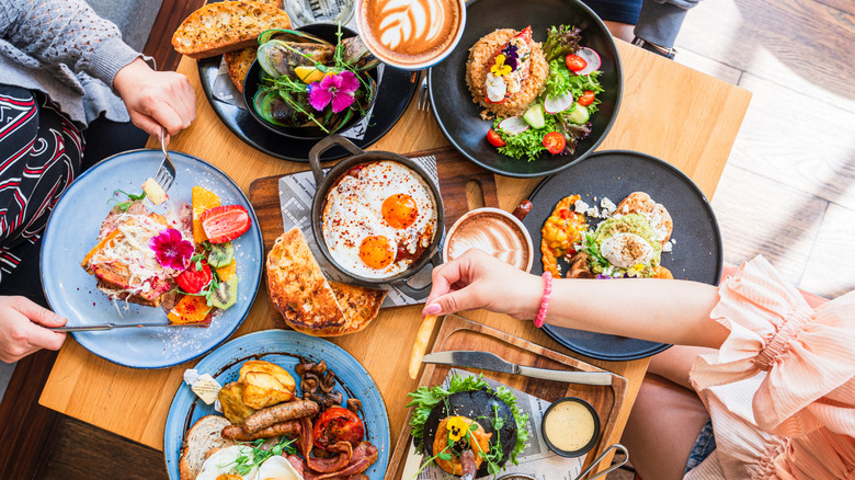 Top-down view of a two people eating breakfast at a table with various dishes