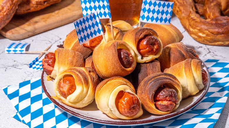 Pigs in a blanket on a white plate on top of a white and blue checkered paper