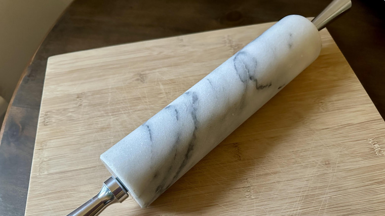 A marble rolling pin on a wooden cutting board.