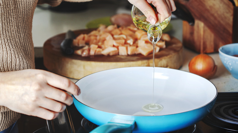 Adding oil to a sauté pan on the stove
