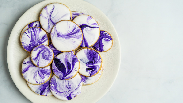 Cookies with marbled purple and white icing on a white plate