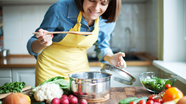 Person smiling while making pot of soup