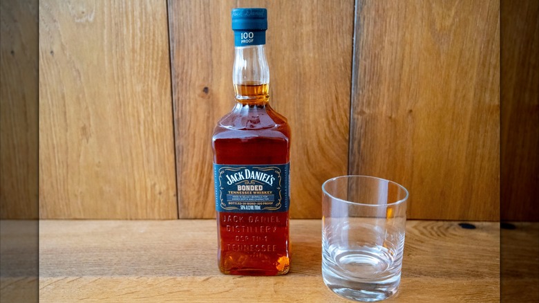 A bottle of Jack Daniel's bonded beside a rocks glass.