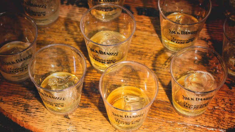 Half-full glasses of Jack Daniel's Whiskey on a barrel table.