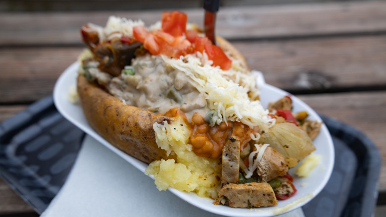 A loaded baked potato with meat, cheese, and veggies.