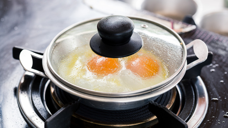 eggs cooking in pan with lid on