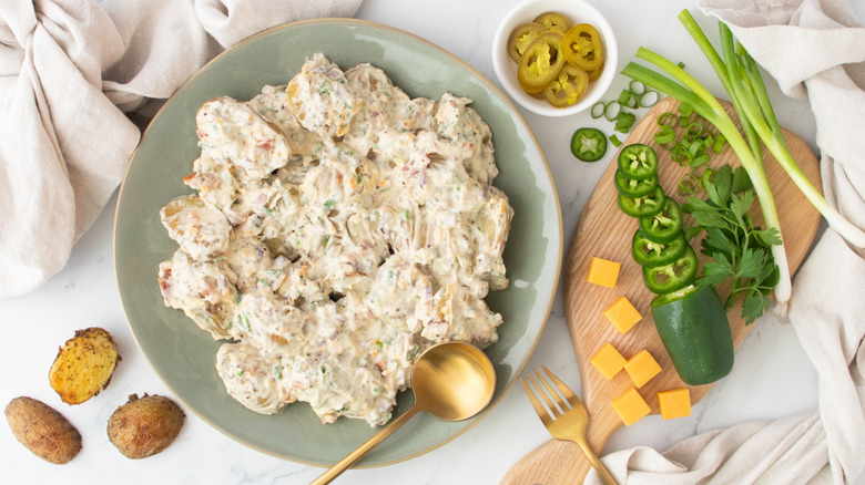 An overhead shot of a large platter with potato salad surrounded by component ingredients