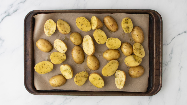 Seasoned raw potatoes on a baking sheet