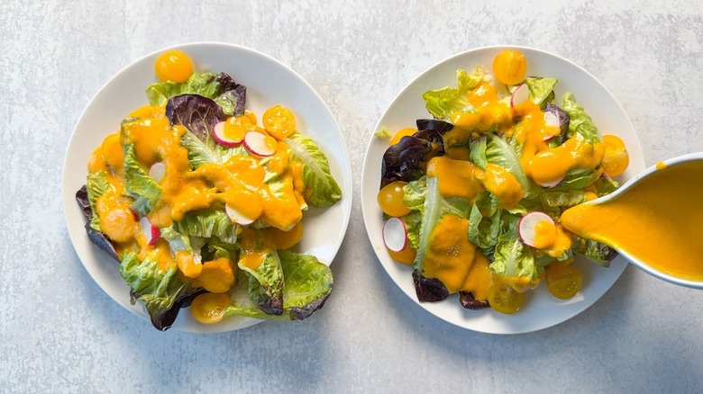 Pouring carrot ginger dressing on salads
