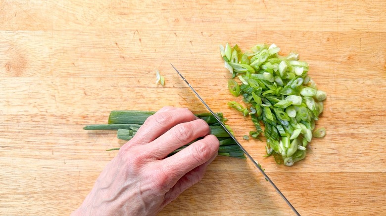 Slicing scallion greens on cutting board