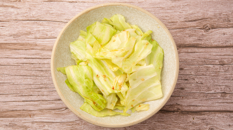 Chopped green cabbage in a bowl with a light dressing and sesame seeds