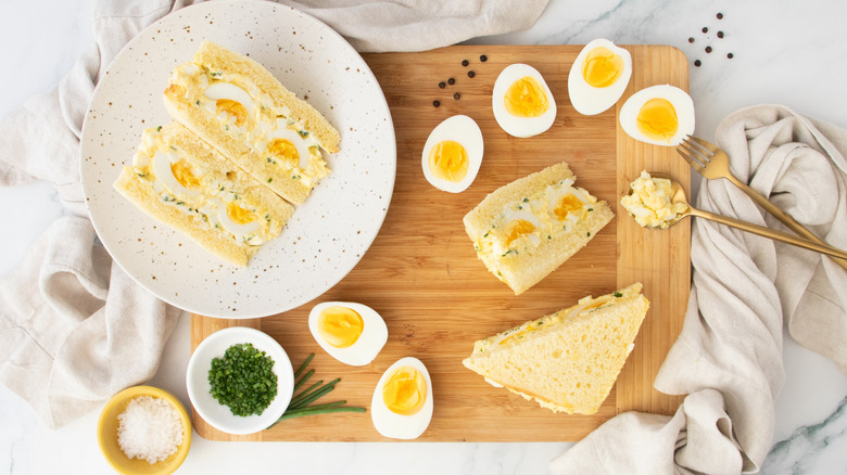 Overhead shot of two egg salad sandwiches and hard boiled eggs