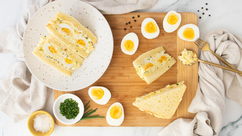 Overhead shot of two egg salad sandwiches and hard boiled eggs