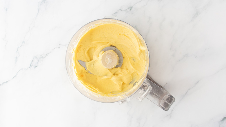A creamy puree of egg yolks in the bowl of a food processor.
