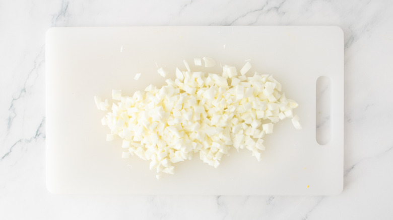 A cutting board with chopped hard boiled egg whites.