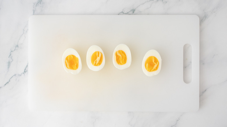 A cutting board with halved soft boiled eggs.
