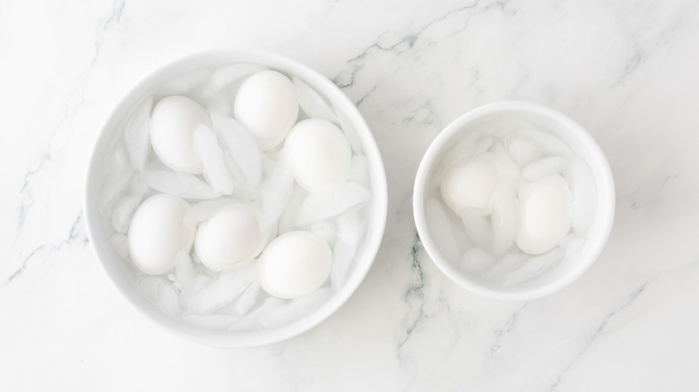 A small bowl and a large bowl with eggs submerged in ice water