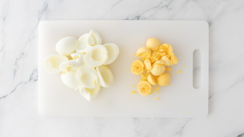 A cutting board with hard boiled egg whites and yolks separated.