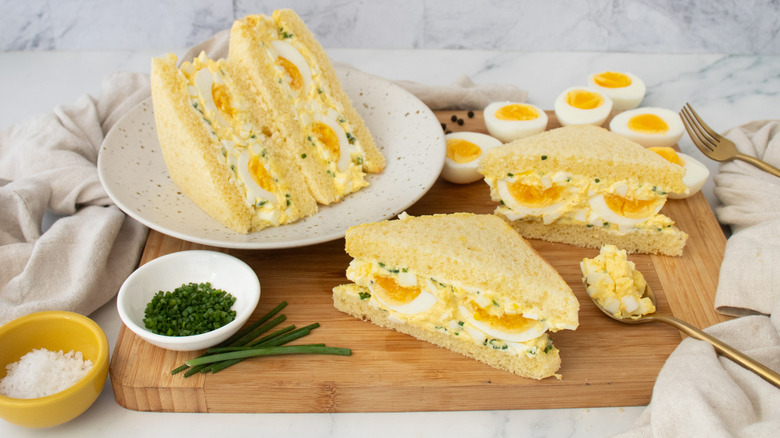 Side shot of egg salad sandwiches and hard boiled eggs