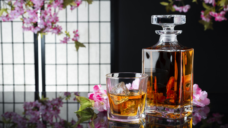 Japanese whisky in a decanter next to flowers and a rocks glass with ice