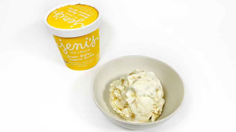 A pint of Jeni's Brown Butter Almond Brittle next to a bowl of ice cream