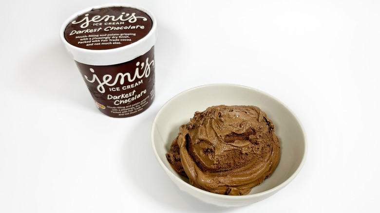 A pint of Jeni's Darkest Chocolate next to a bowl of ice cream