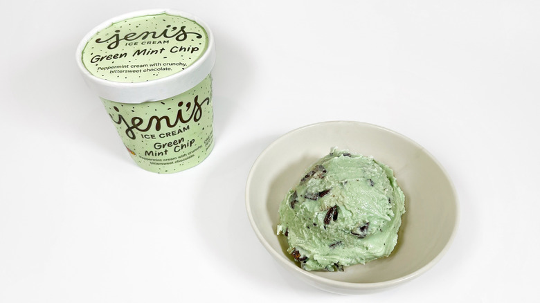 A pint of Jeni's Green Mint Chip next to a bowl with a scoop