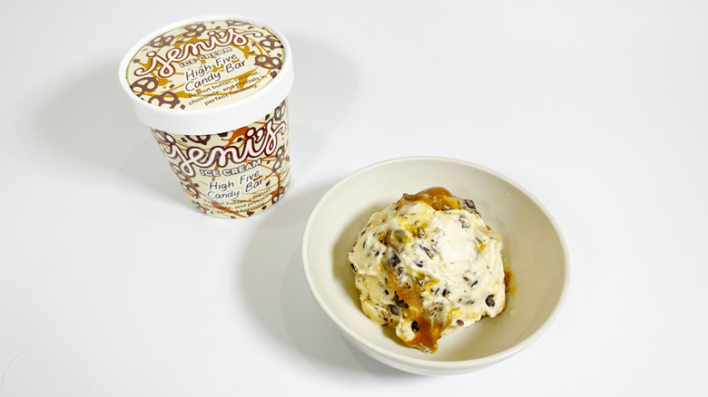 A pint of Jeni's High Five Candy Bar next to a bowl of ice cream