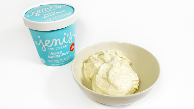 A pint of Jeni's Honey Vanilla Bean next to a bowl of ice cream