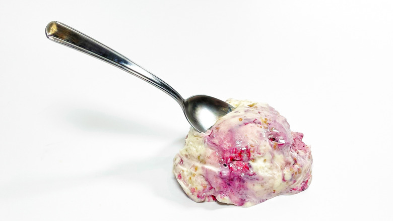 A scoop of ice cream on a white background with a spoon protruding
