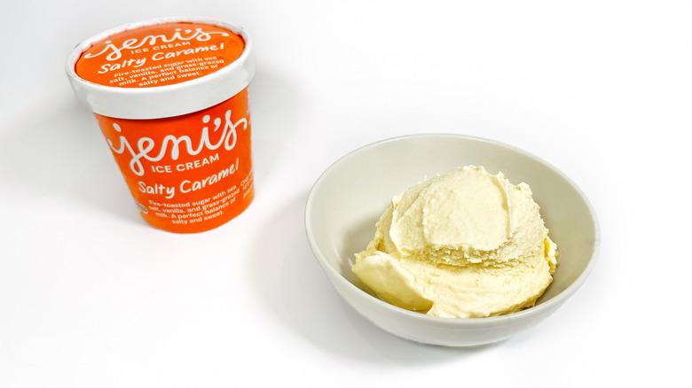 A pint of Jeni's Salty Caramel next to a bowl with a scoop
