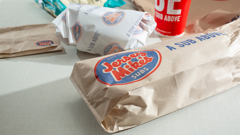 A Jersey Mikes order on a table including a sandwich, drink, and chips