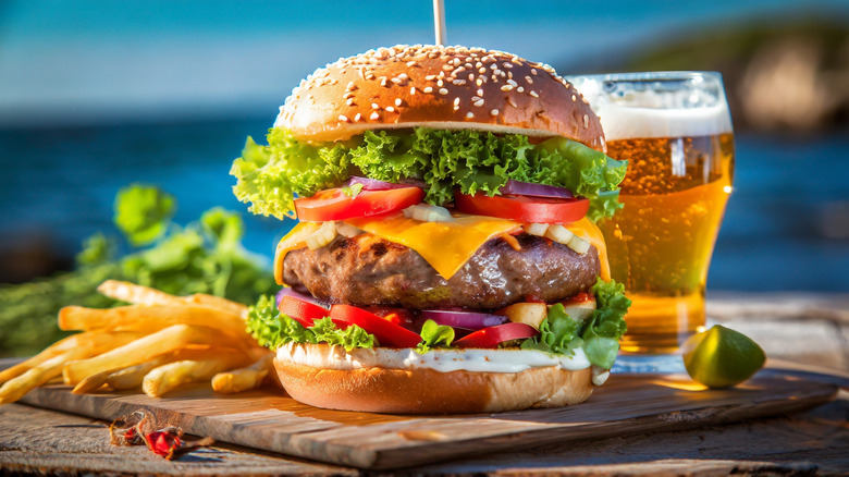 A cheeseburger with fries and a beer in a tropical locale