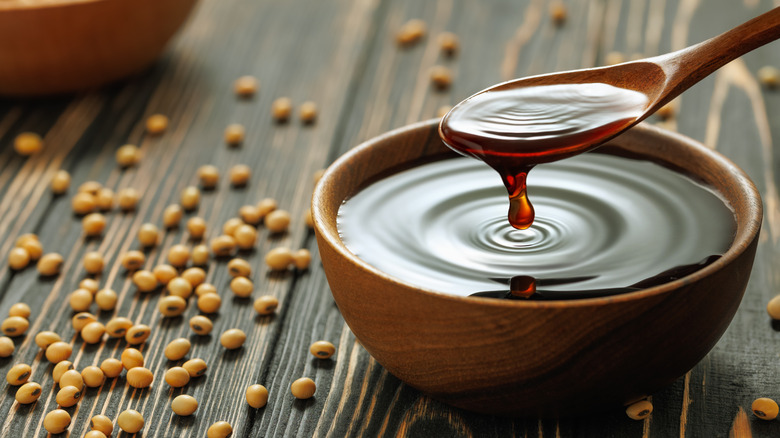Soy sauce dripping from a spoon into a bowl.
