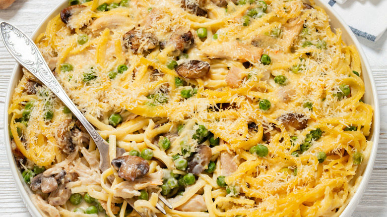 baked spaghetti in baking dish on white wooden table with ingredients, vertical view