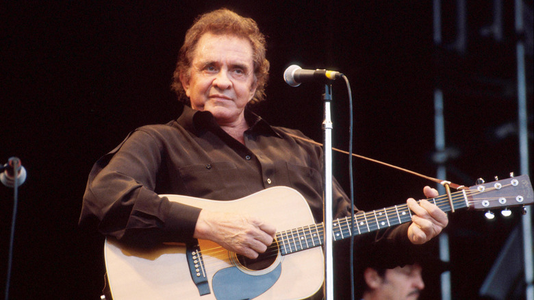 Johnny Cash performing in signature all-black with his acoustic guitar.