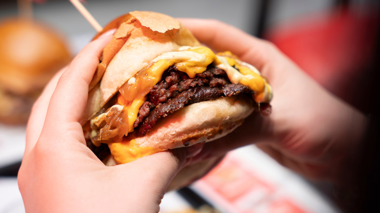 Hands holding a cheeseburger