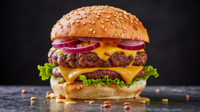 Double cheeseburger with lettuce and red onion on a sesame seed bun