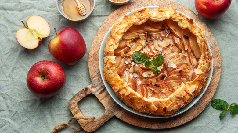 apple tart on a wooden board with apples around it